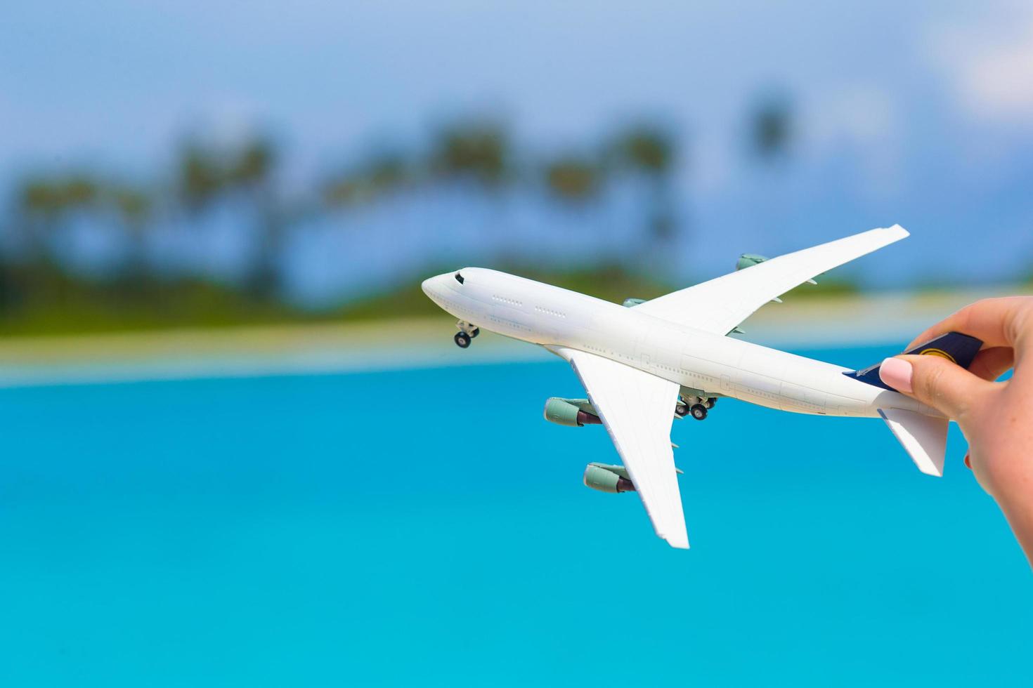 litet vitt leksaksflygplan mot ett turkos hav foto