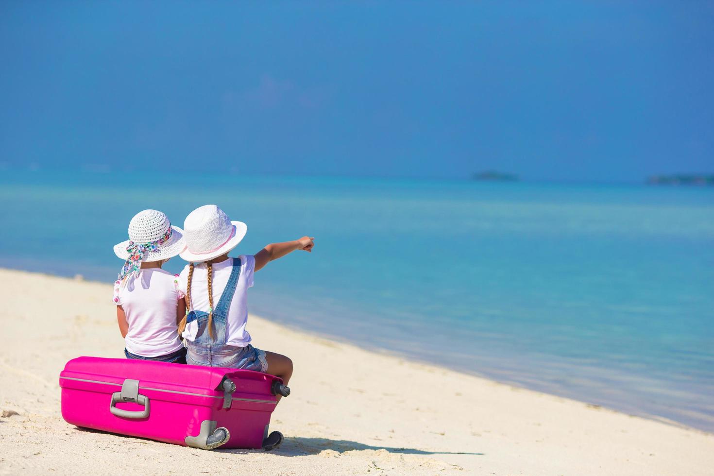 två flickor som sitter på bagage på en strand foto