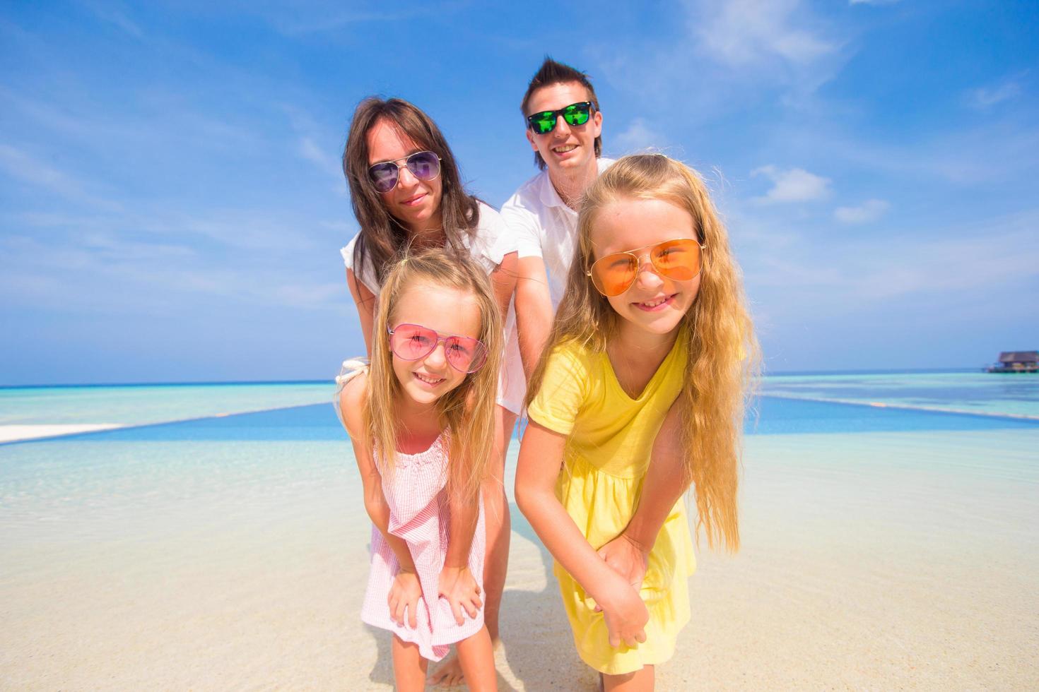 familj poserar för ett porträtt på en strand foto