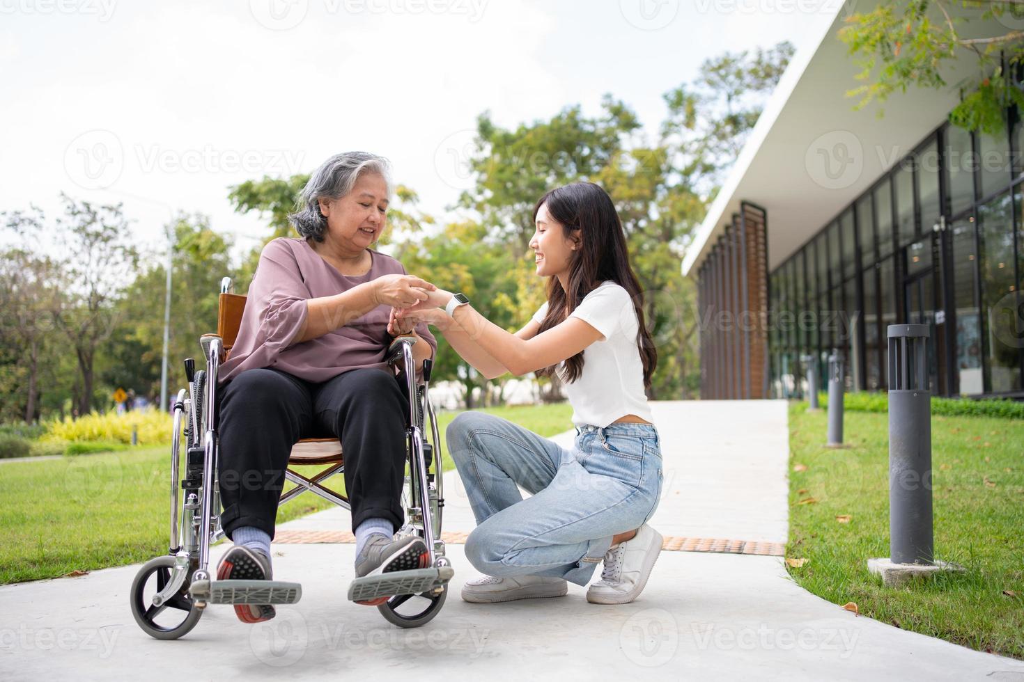 asiatisk försiktig vårdgivare eller sjuksköterska håll de patient hand och uppmuntra de patient i en rullstol. begrepp av Lycklig pensionering med vård från en vårdgivare och besparingar och senior hälsa försäkring. foto