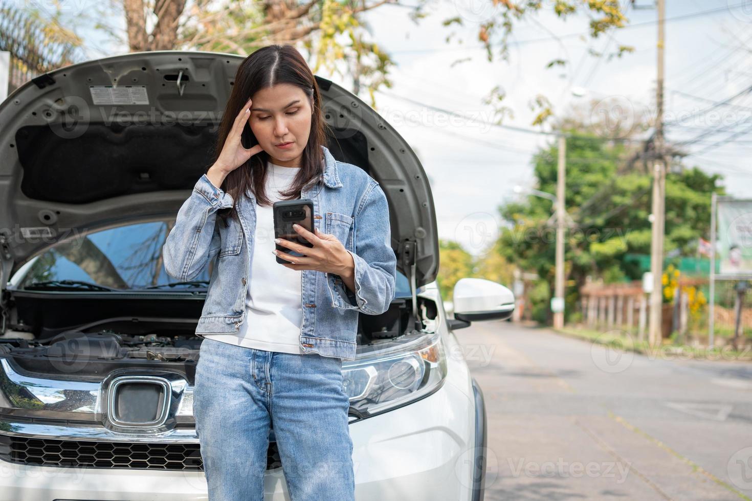 arg asiatisk kvinna och använder mobiltelefon som ringer efter hjälp efter ett bilhaveri på gatan. koncept av fordonsmotorproblem eller olycka och nödhjälp från professionell mekaniker foto