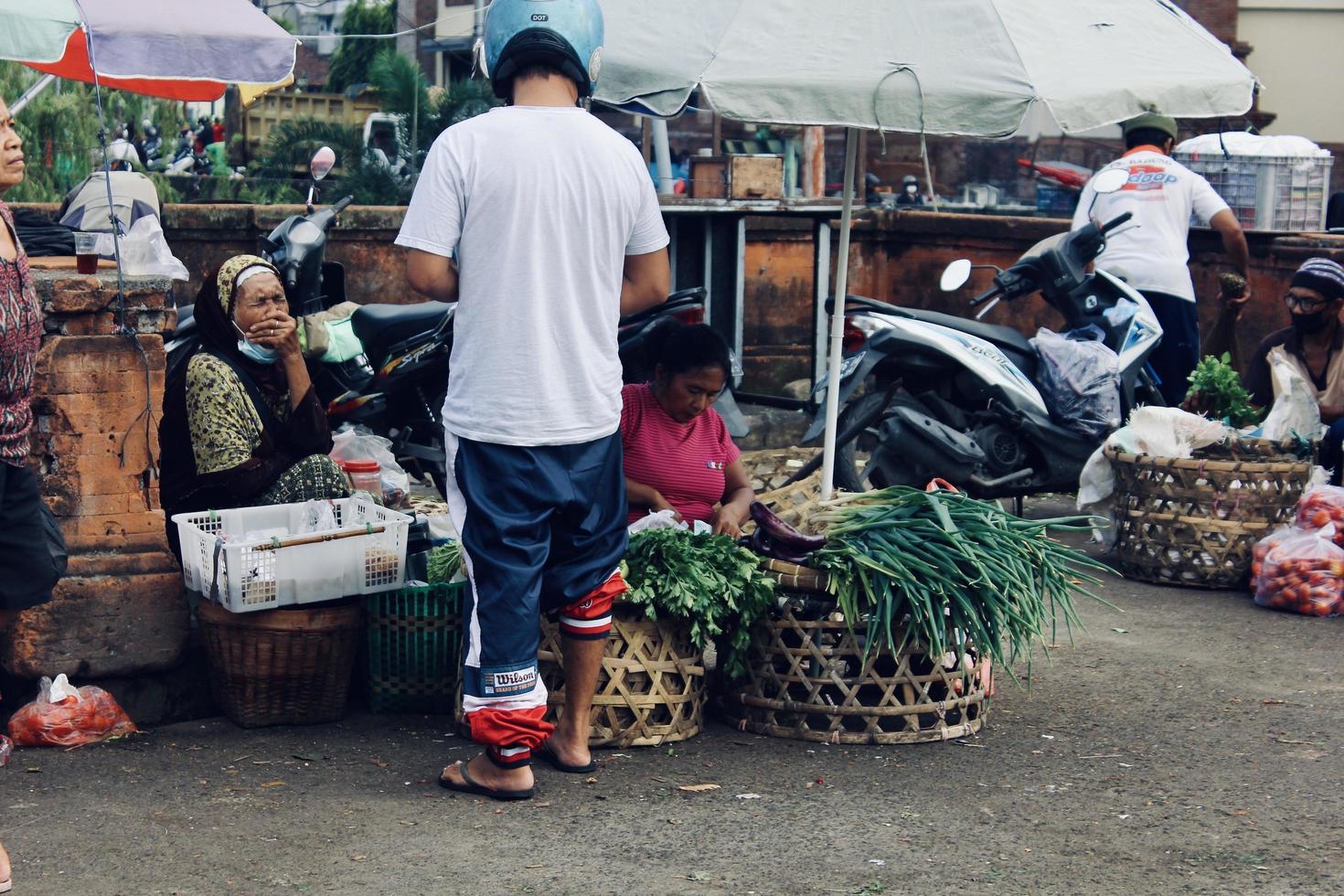 badung bali januari 13 2023 en köpare är sett uppköp färsk frukt och grönsaker på en traditionell marknadsföra i bali foto