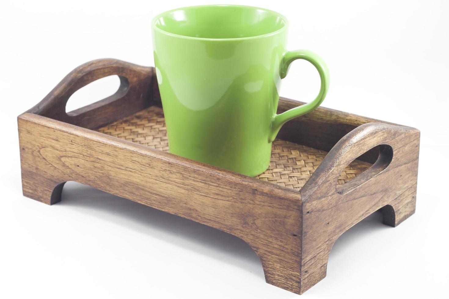 grönt kaffekopp på en träbricka foto