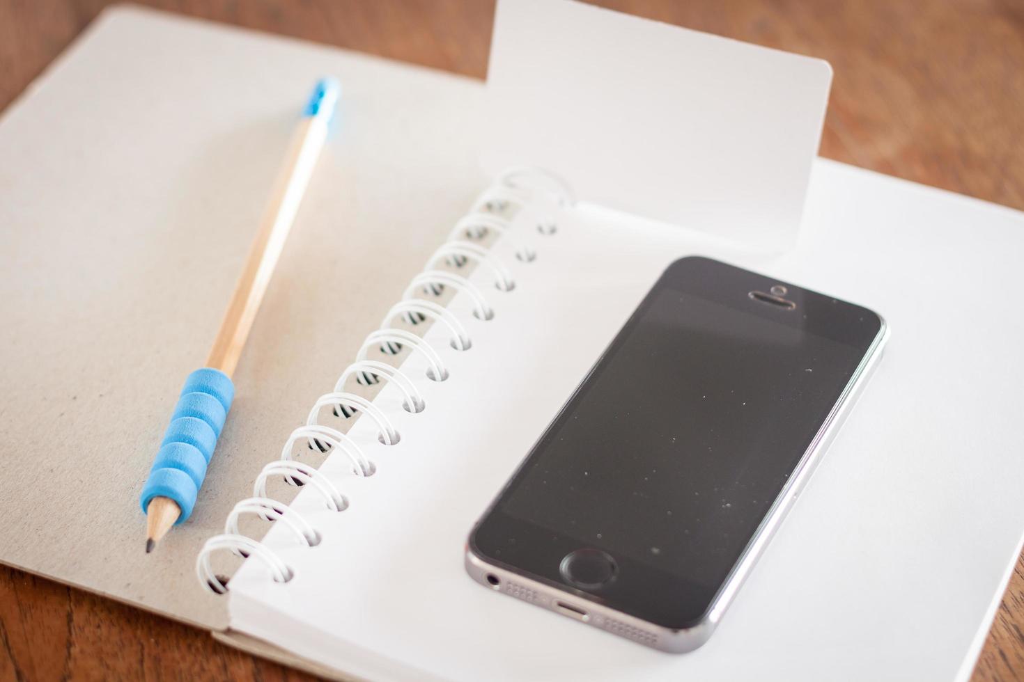 visitkort och en telefon på en öppen anteckningsbok foto