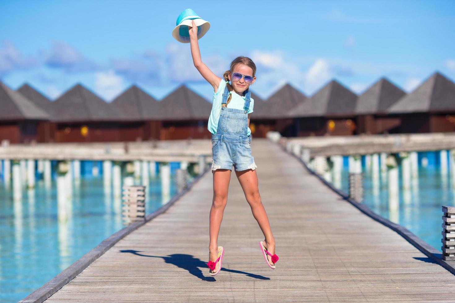 Maldiverna, Sydasien, 2020 - flicka som har kul på träbrygga nära vattenbungalower foto