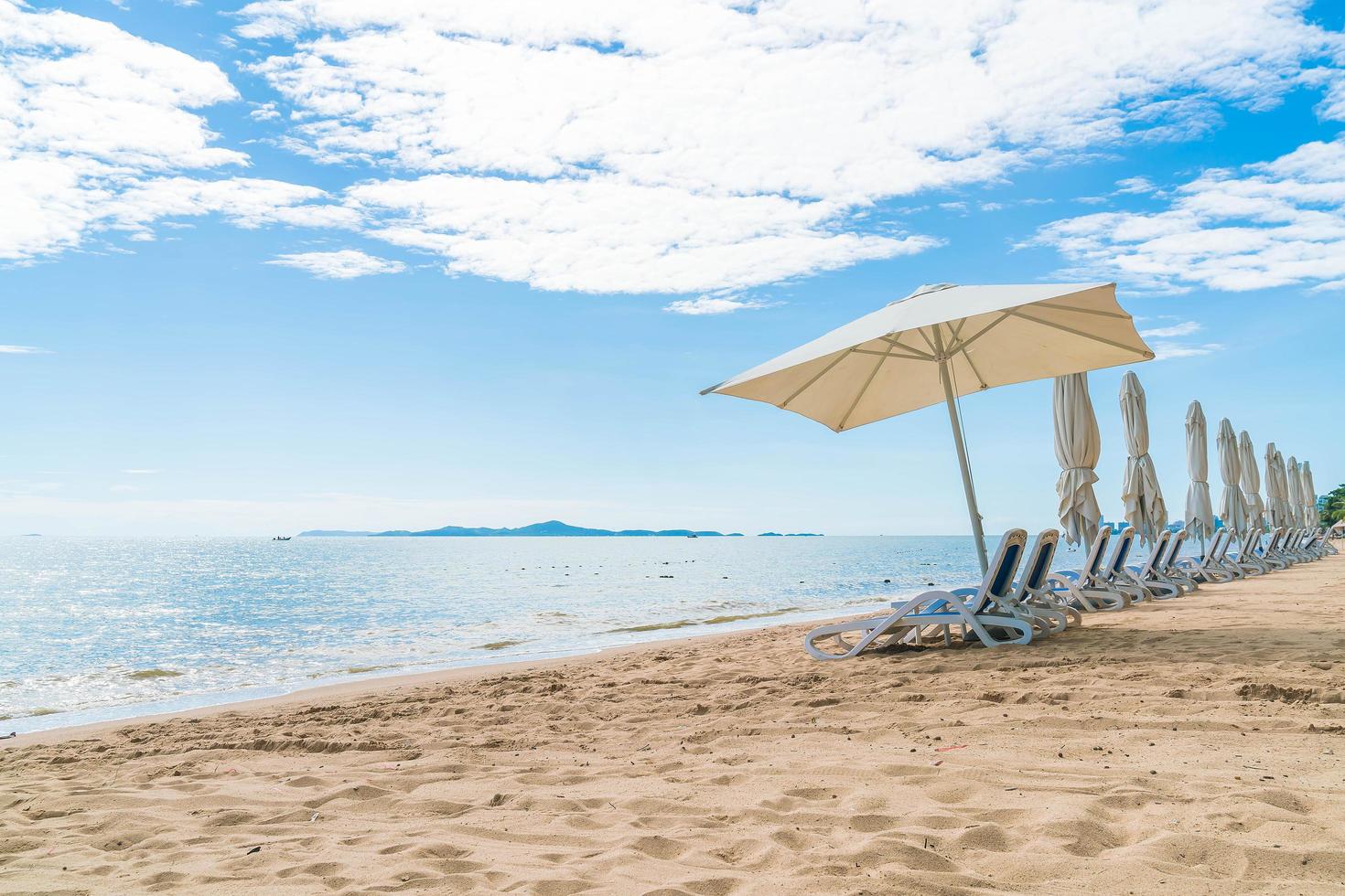 paraply och stolar på den härliga tropiska stranden och havet foto