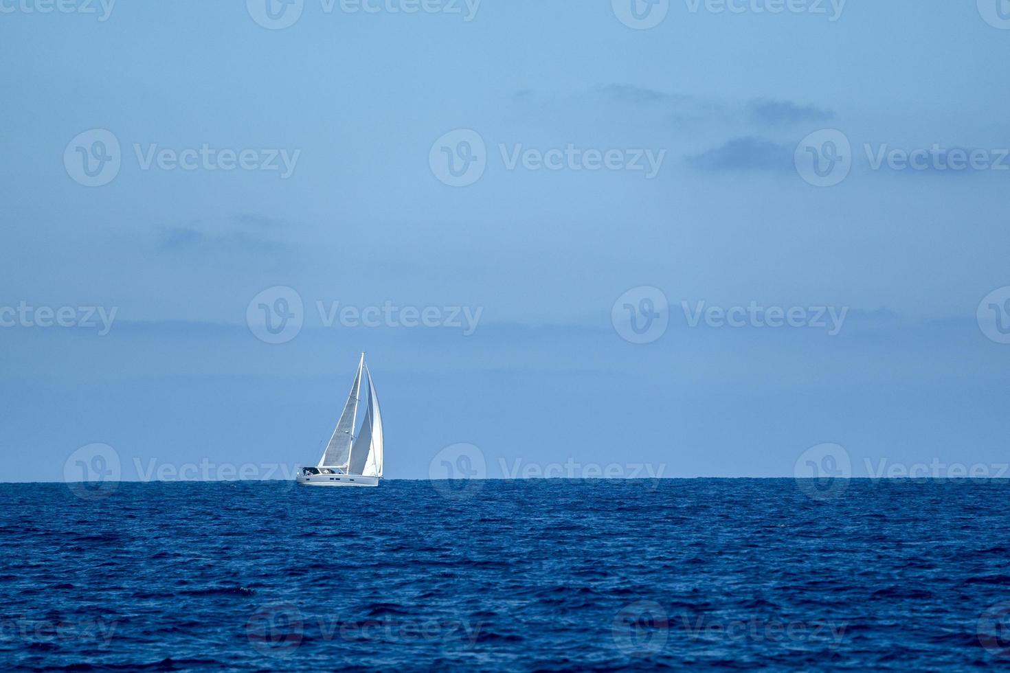 små segelbåt på djup blå hav foto