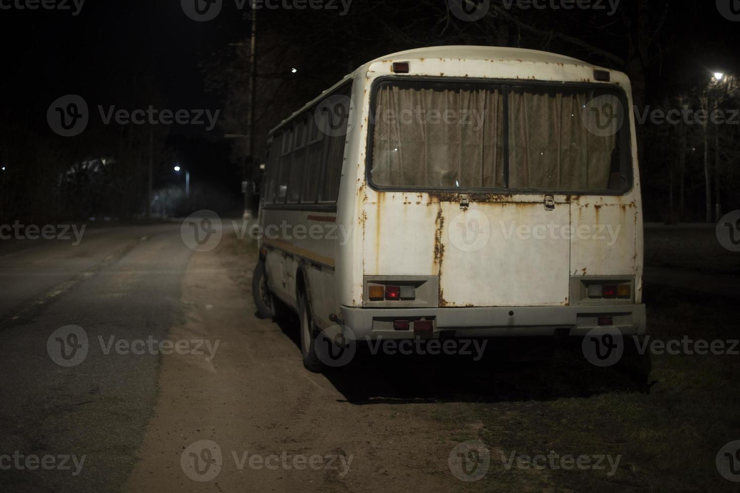 vit buss är på sida av väg på natt. olaglig parkering längs väg. foto