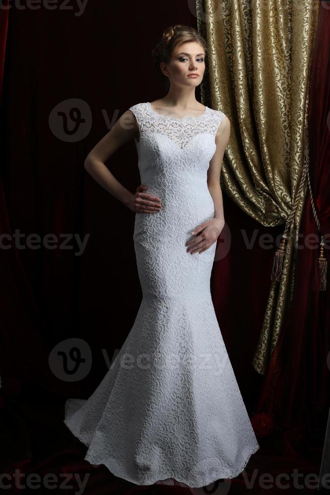 skön brud i en vit klänning på en mörk bakgrund. bröllop mode och salong. foto