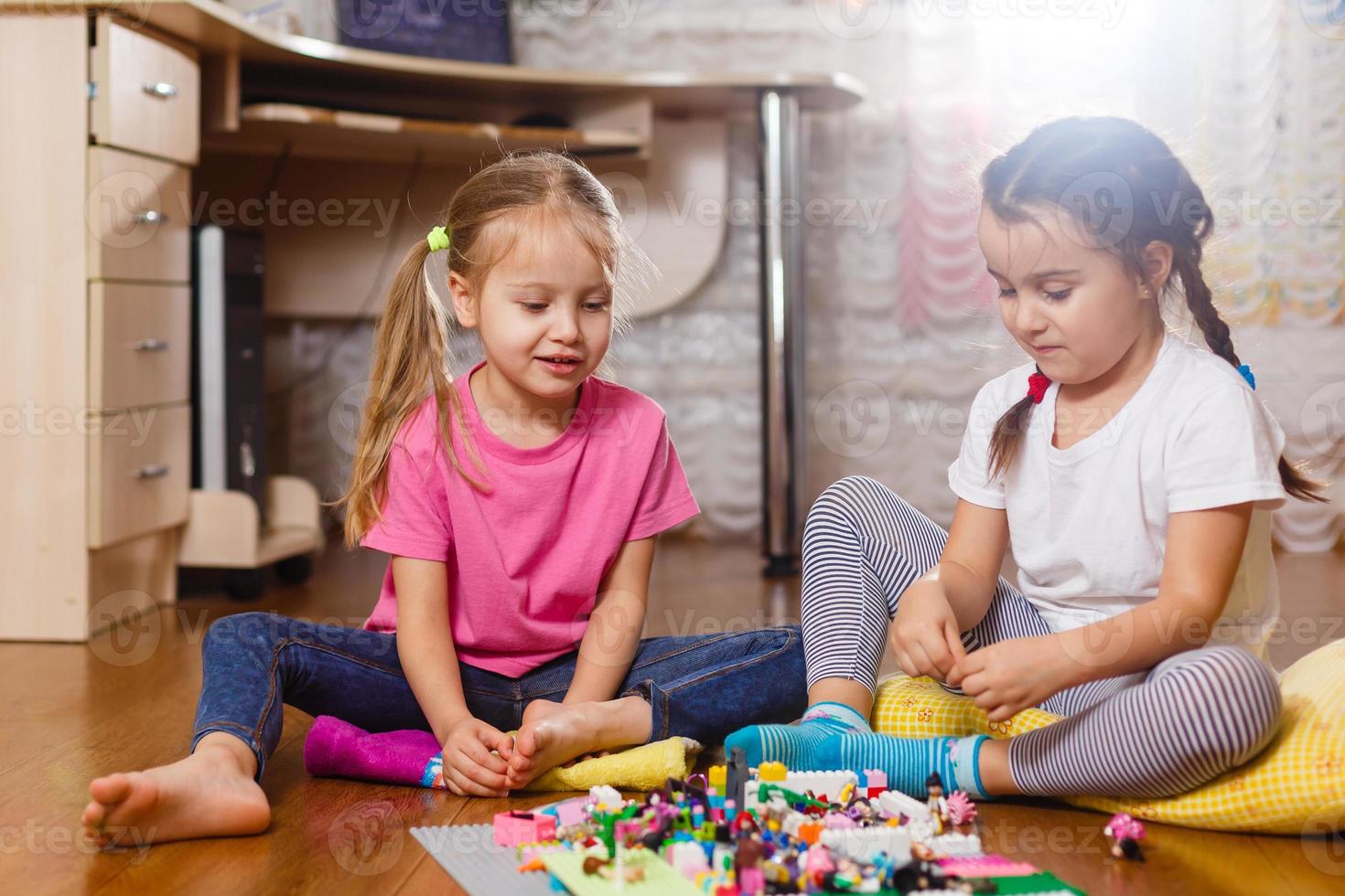två söt liten barn är spelar med block Lycklig flickor på Hem rolig härlig systrar foto