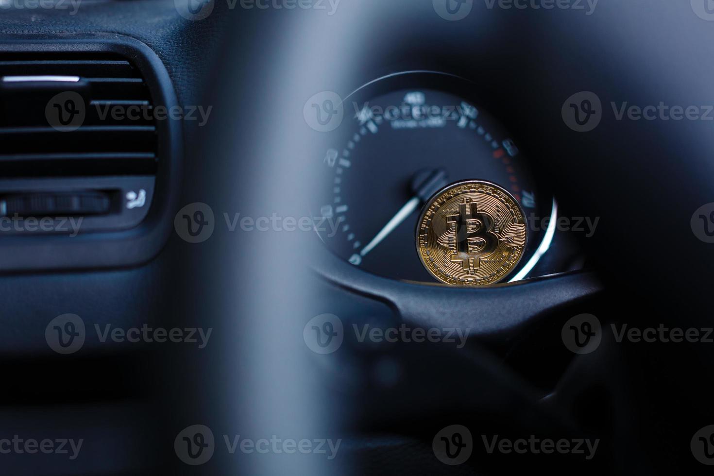 mynt är en guld bitcoin på de instrumentbräda av de bil Nästa till de bränsle konsumtion foto