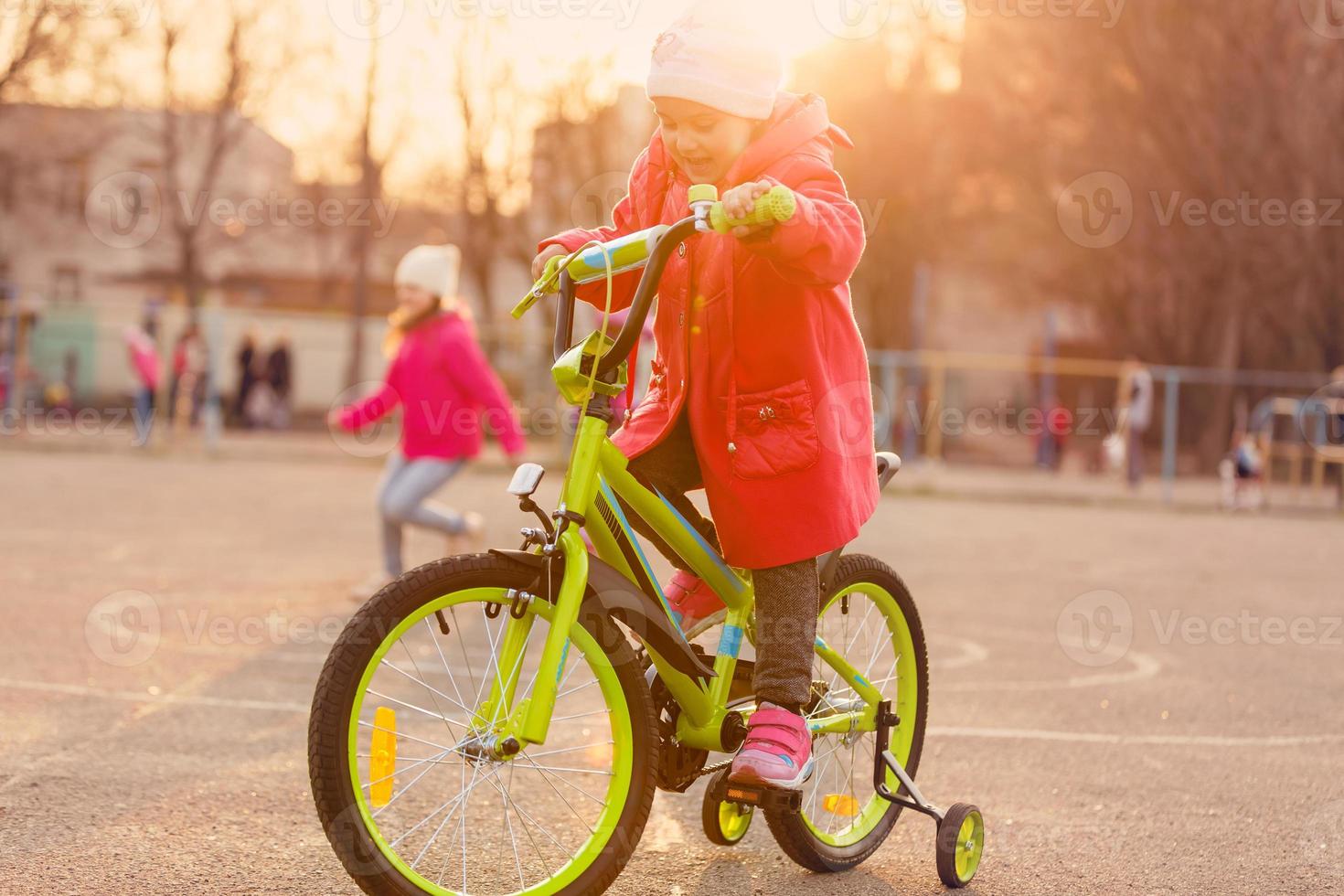 skön leende liten flicka ridning cykel i en parkera foto