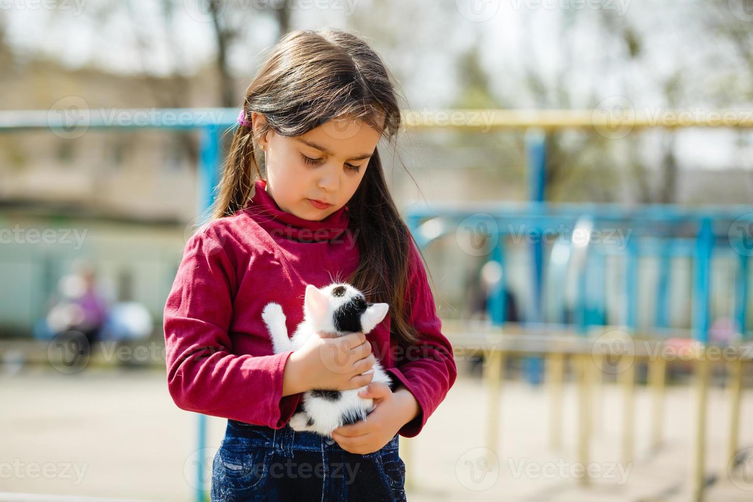 utomhus- porträtt av ung barn flicka med små kattunge, flicka spelar med katt på naturlig bakgrund foto