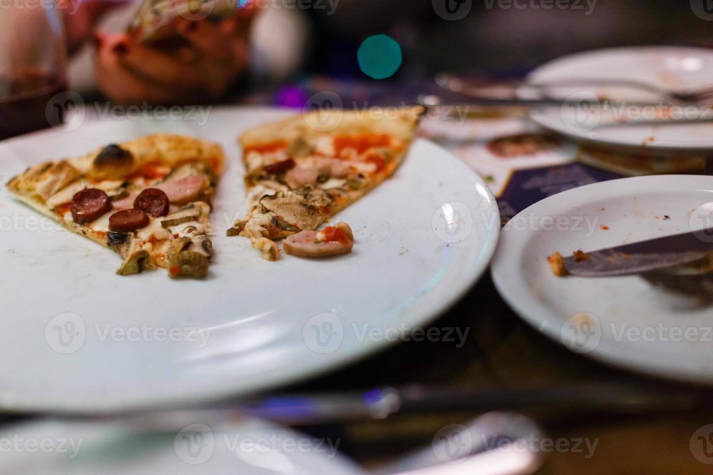 tallrik med en skiva av pizza på en timrad tabell foto