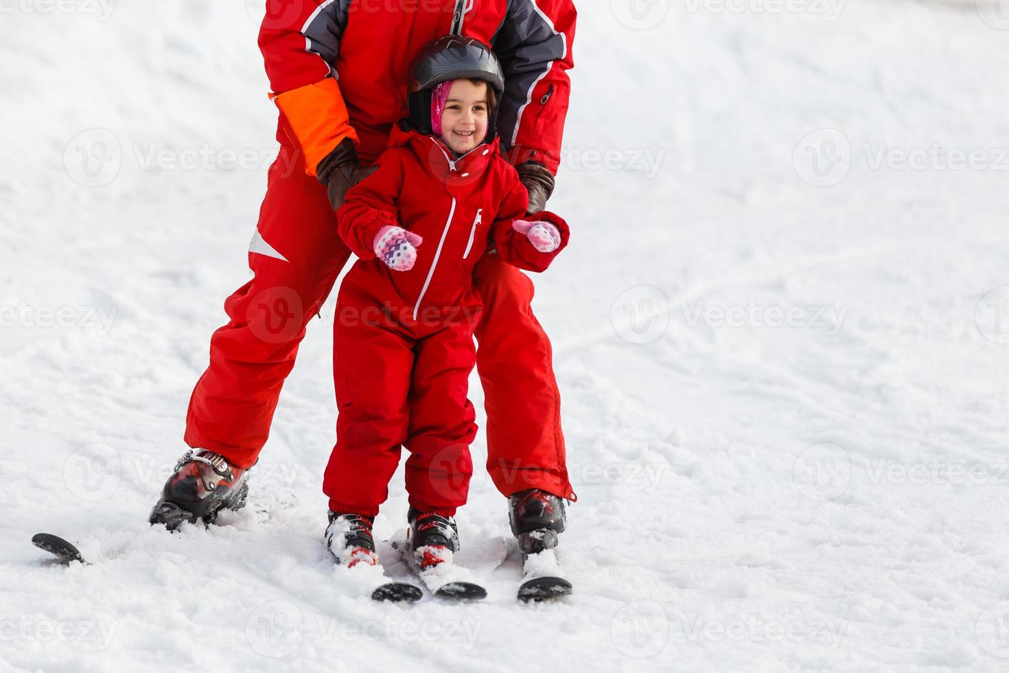 professionell åka skidor instruktör är undervisning en barn till åka skidor på en solig dag på en berg backe tillflykt med Sol och snö. familj och barn aktiva semester. foto