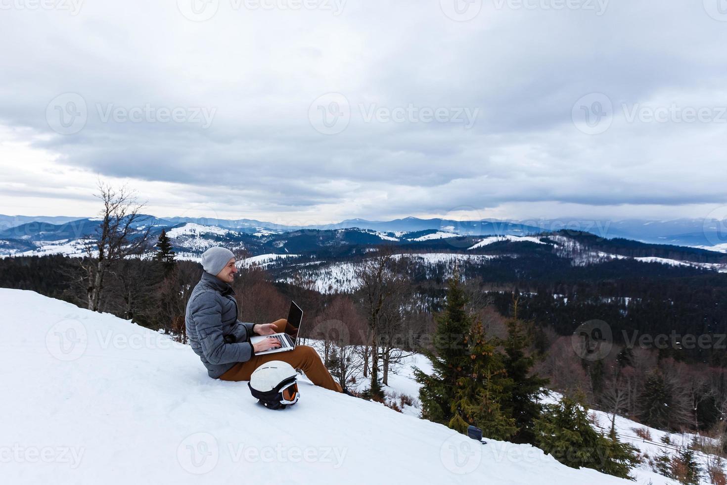 en ung man med en bärbar dator Sammanträde på klippa kant på berg topp foto