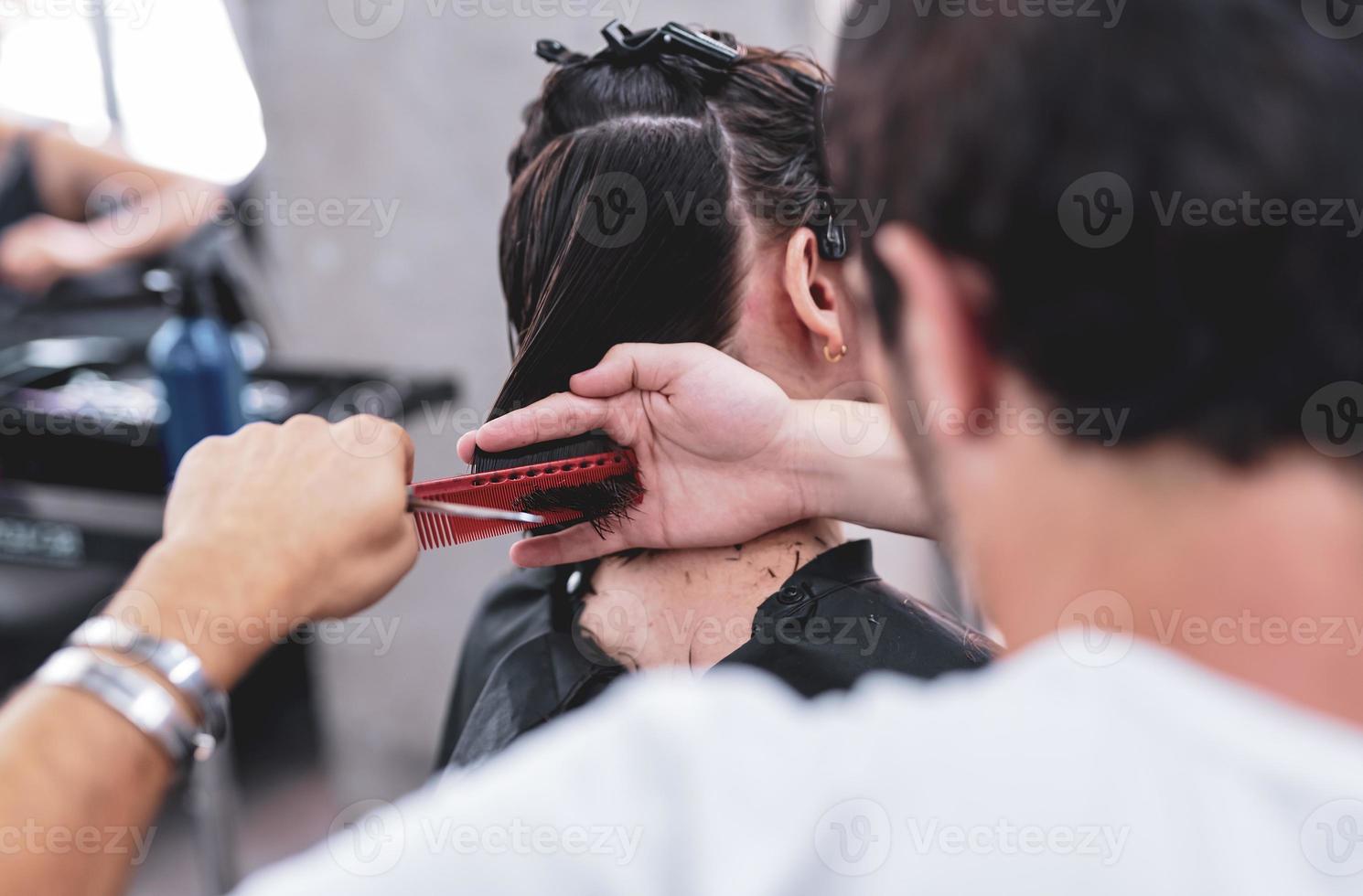 Foto av en coiffeur trimning de klient våt hår slutar använder sig av en hårkam och en par av sax