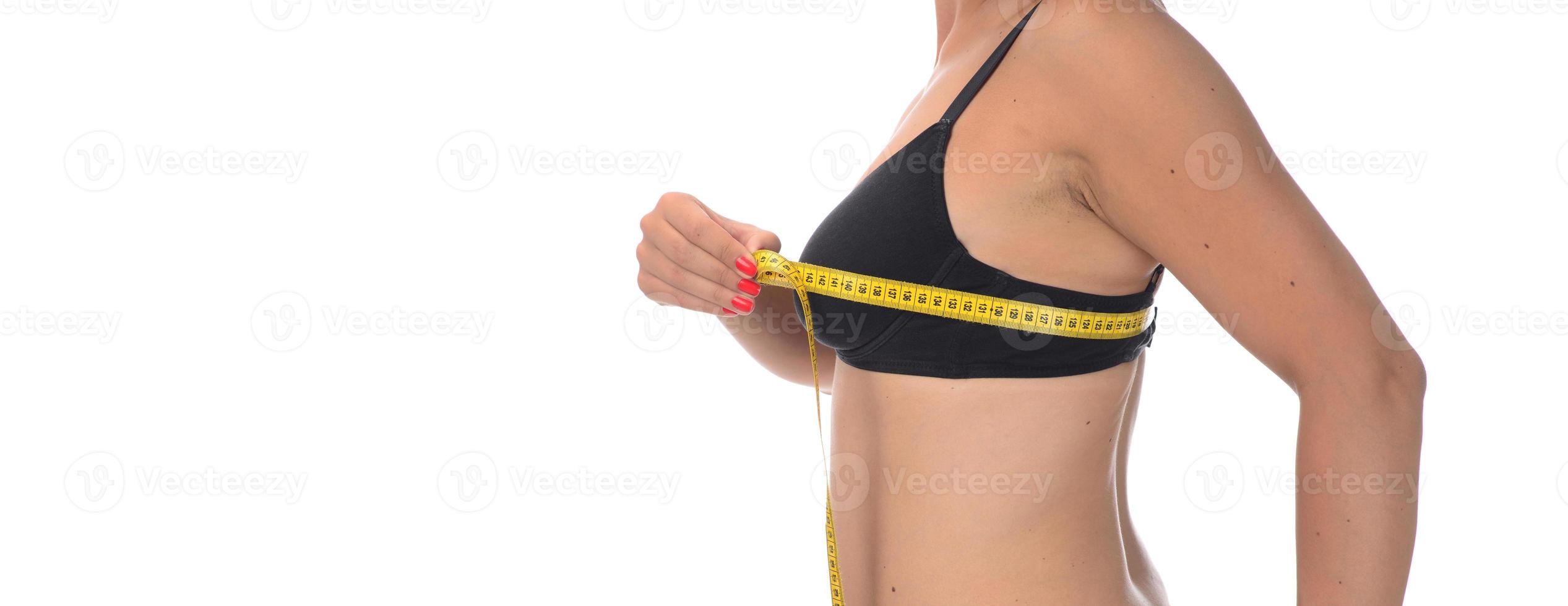 sportig kvinna mätning upp henne bröst, isolerat i vit foto