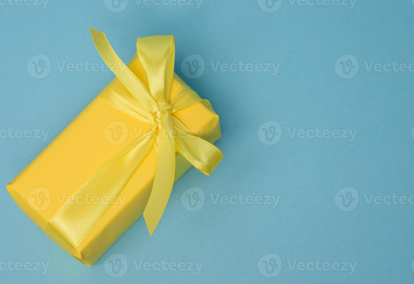 rektangulär låda med en gåva insvept i gul papper och bunden med en silke gul band foto