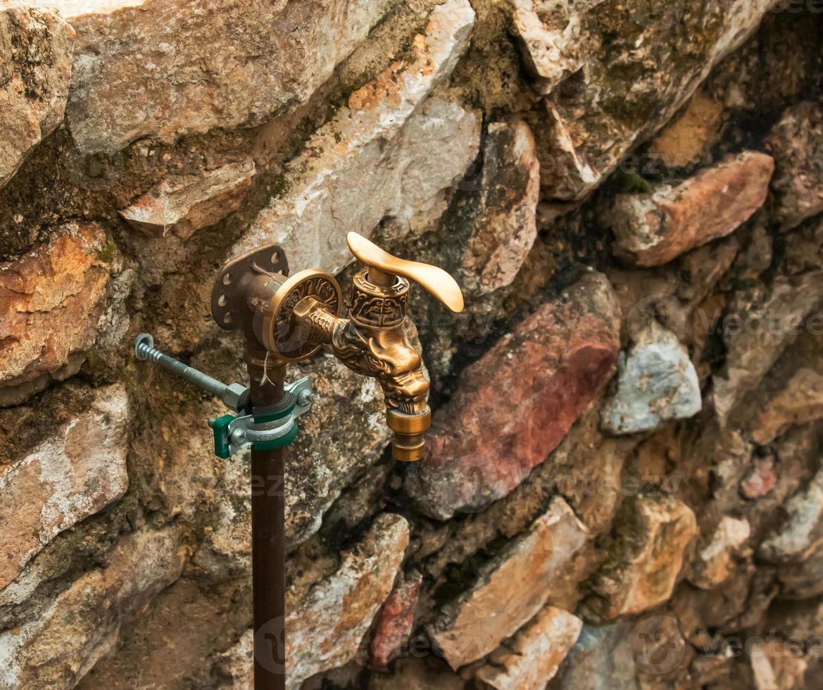 antik mässing vatten kran som ett arkitektonisk monument. gammal kran med vatten på de gata. foto