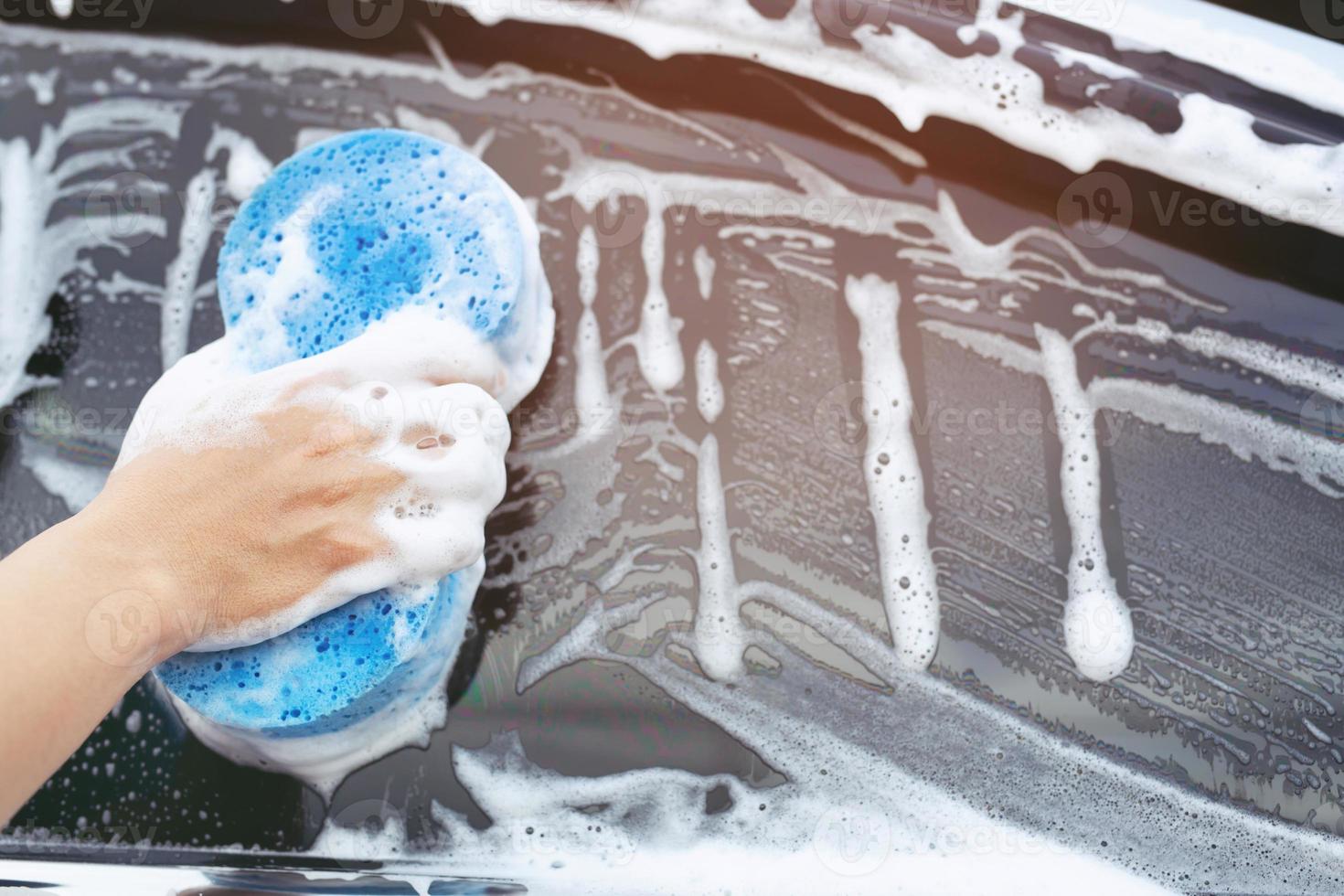 människor arbetare man håller handen blå svamp och bubbla skum rengöringsmedel fönster för att tvätta bil. konceptbil tvätt ren. lämna utrymme för att skriva meddelanden. foto