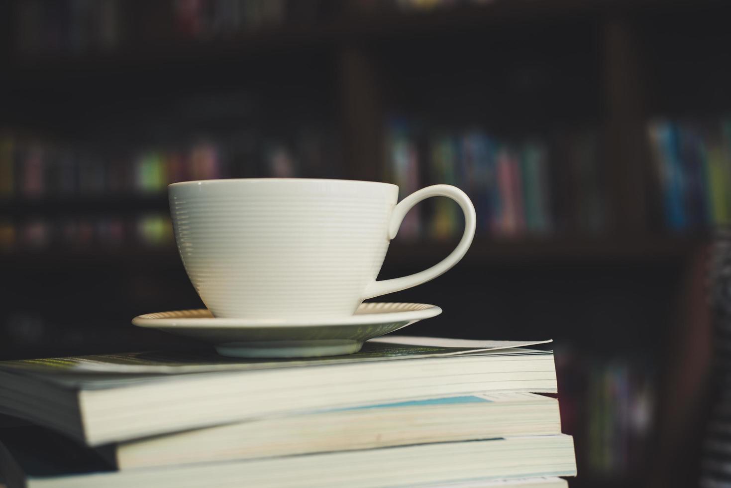kaffekopp och bunt med böcker på träbord foto