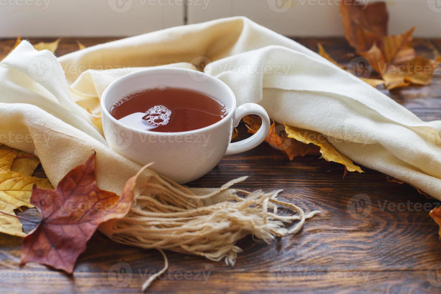 höst löv med en kopp av te eller kaffe Nästa till en scarf på en trä- bakgrund med kopia Plats foto