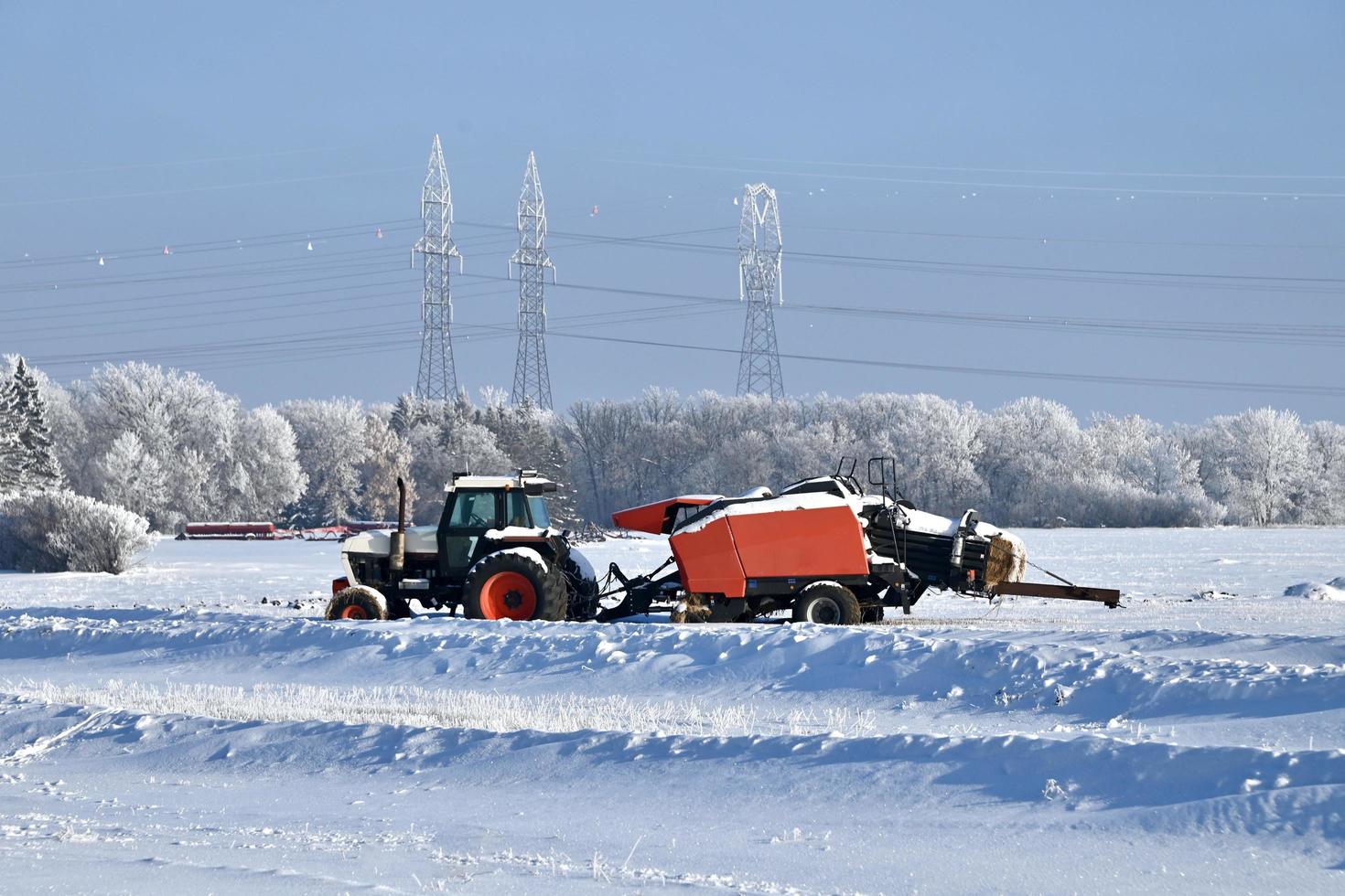 en snö täckt bruka traktor och balpress i en frysta fält foto
