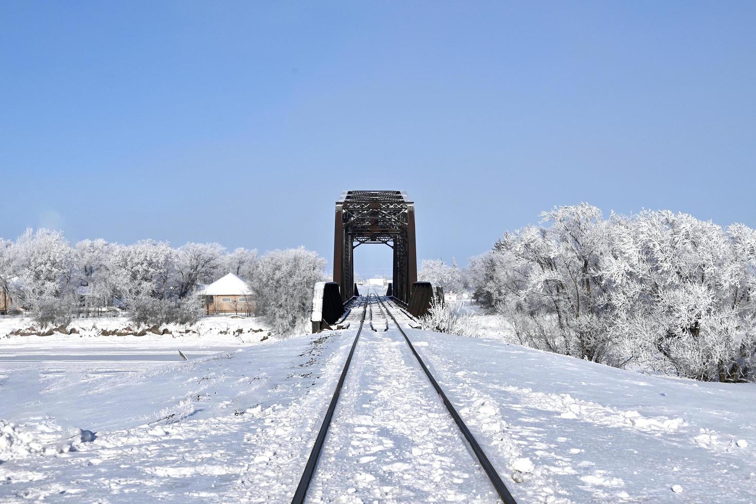 järnväg spår leda genom de snö till en bro foto