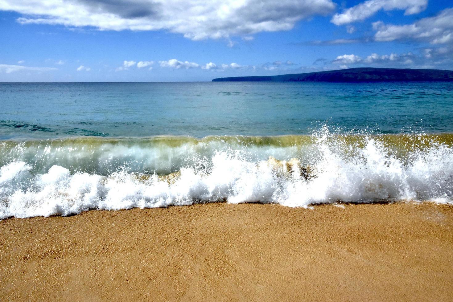 vågor kraschar på en strand i maui foto