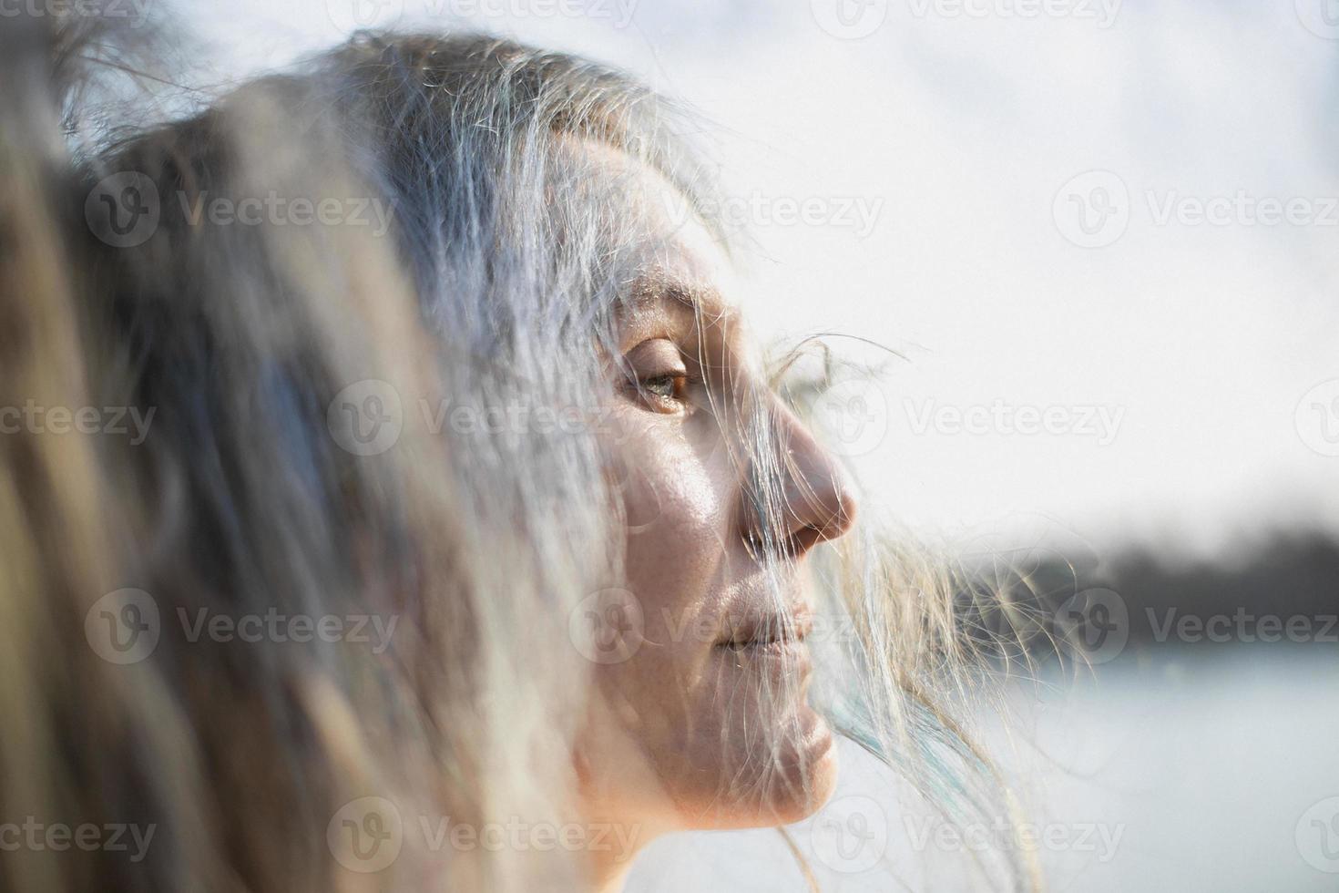 stänga upp kvinna med halv stängd ögon och silver- hår faller på ansikte porträtt bild foto