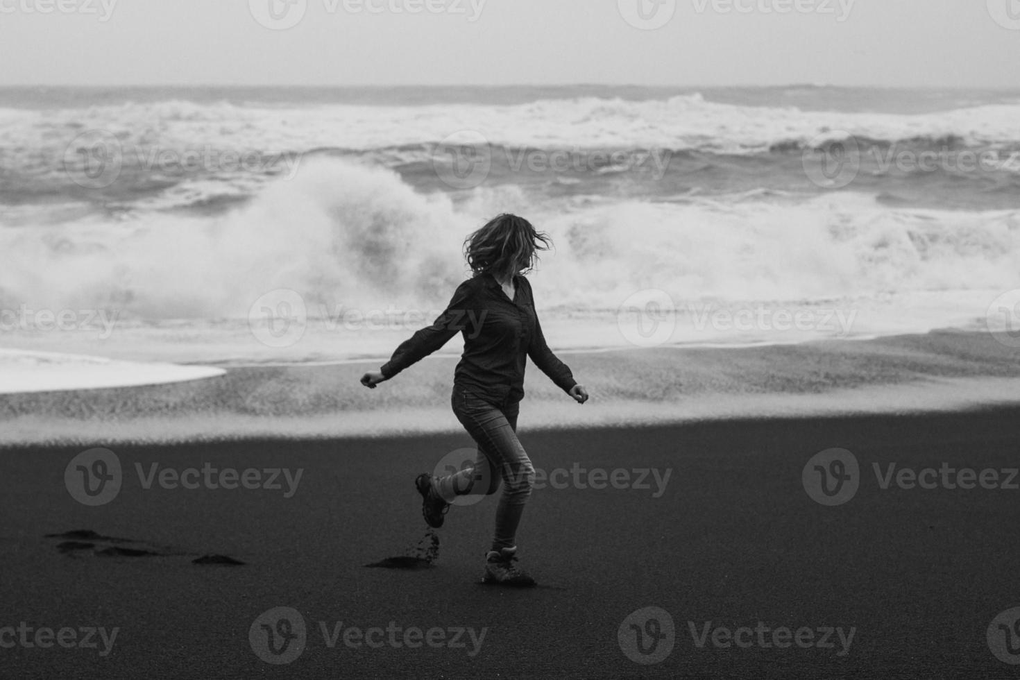 turist löpning längs reynisfjara strand svartvit naturskön fotografi foto