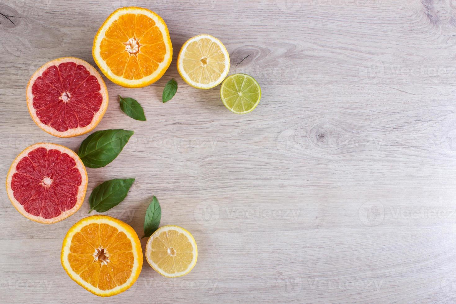 saftig citrus- frukt skära bakgrund mynta blad. apelsiner, citroner, limefrukter, grapefrukt, mynta löv på en ljus trä- bakgrund foto