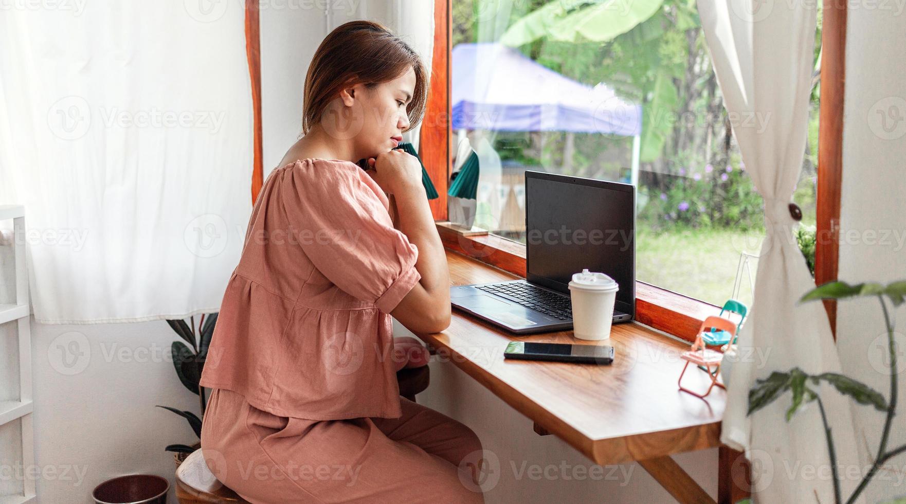 en Lycklig kvinna på en Kafé använder sig av en bärbar dator. ung vit kvinna Sammanträde i en kaffe affär upptagen arbetssätt på henne bärbar dator. foto