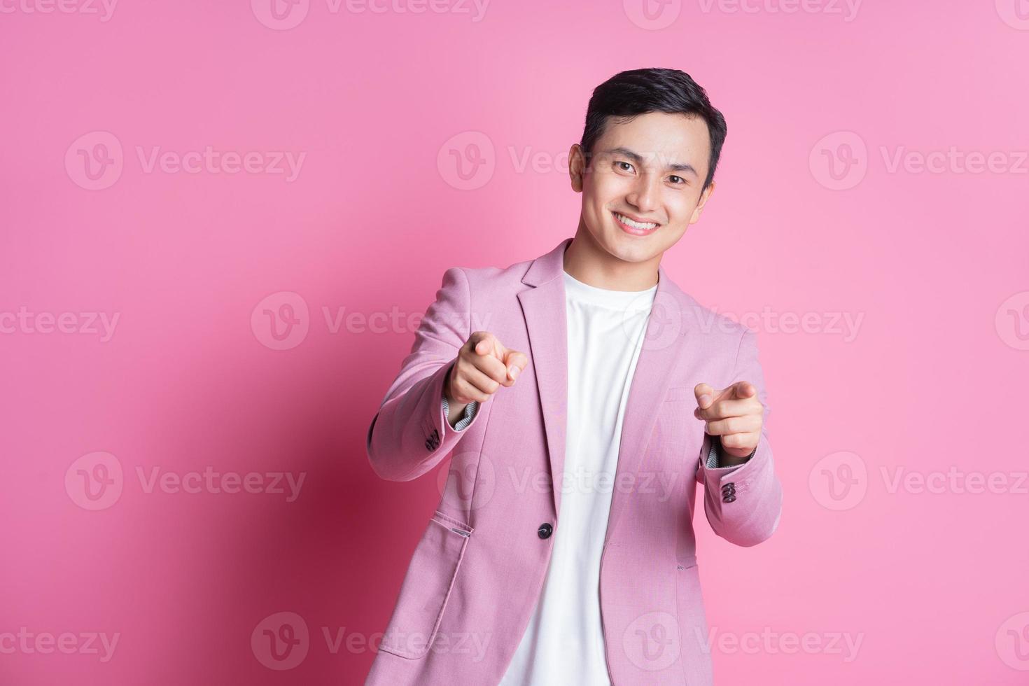 porträtt av ung asiatisk man bär rosa kostym Framställ på bakgrund foto