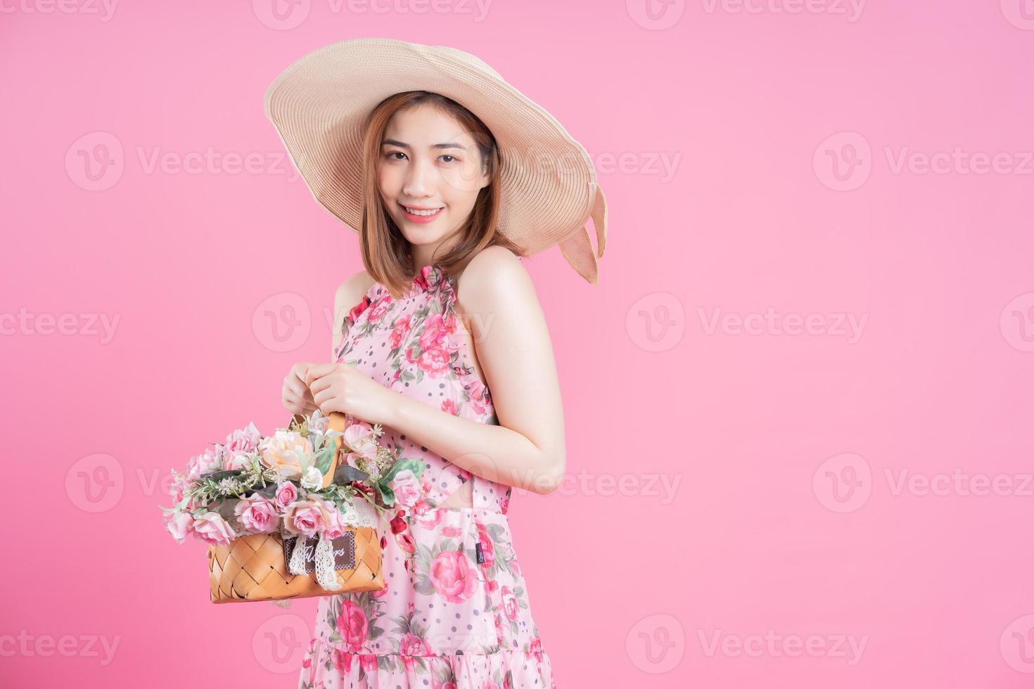 Foto av ung asiatisk flicka bär blomma klänning på rosa bakgrund