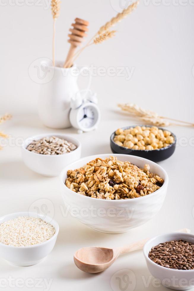 bakad granola i en skål och annorlunda frön i skålar på de tabell. friska frukost. vertikal se foto