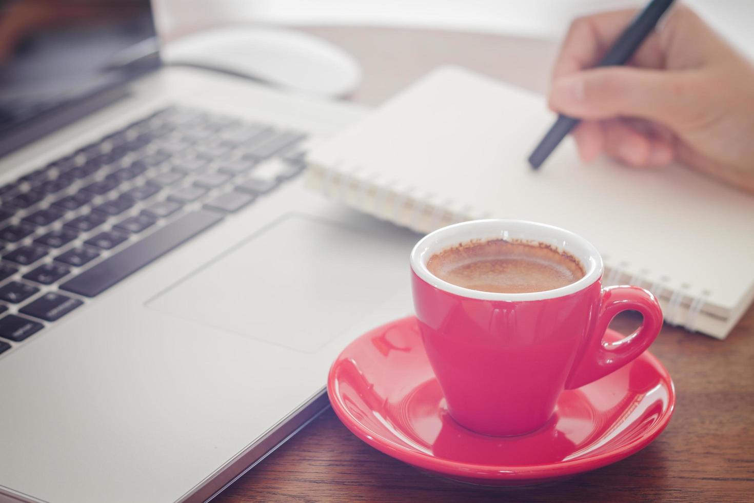 röd kaffekopp en person som skriver i en anteckningsbok foto