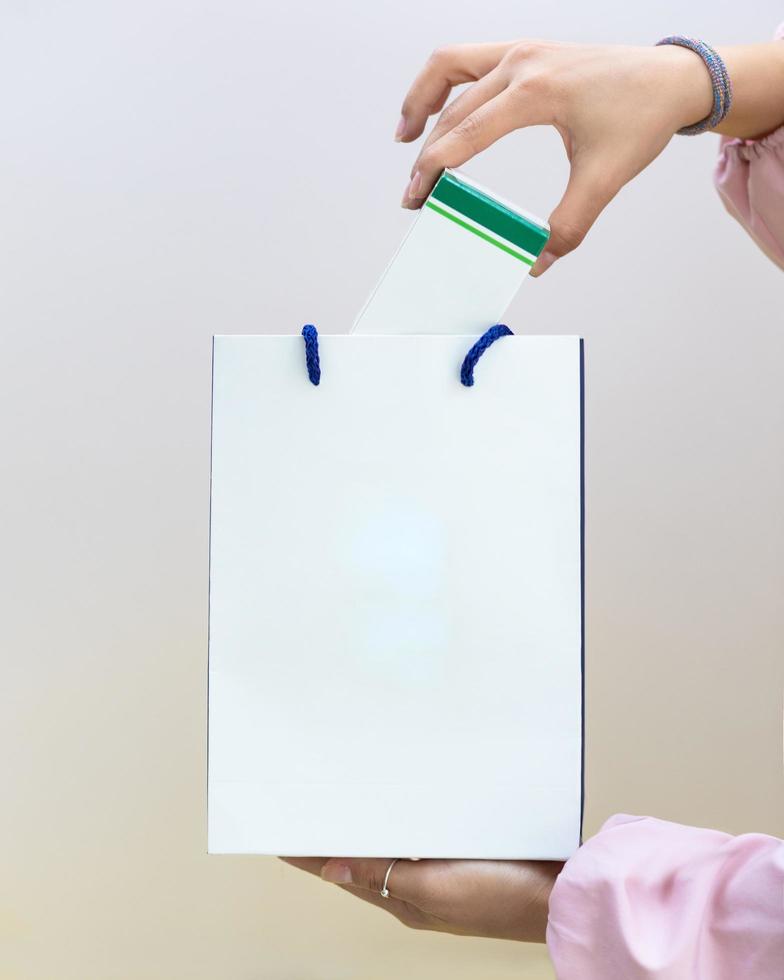 kvinna som sätter en låda i den vita shoppingpåsen foto