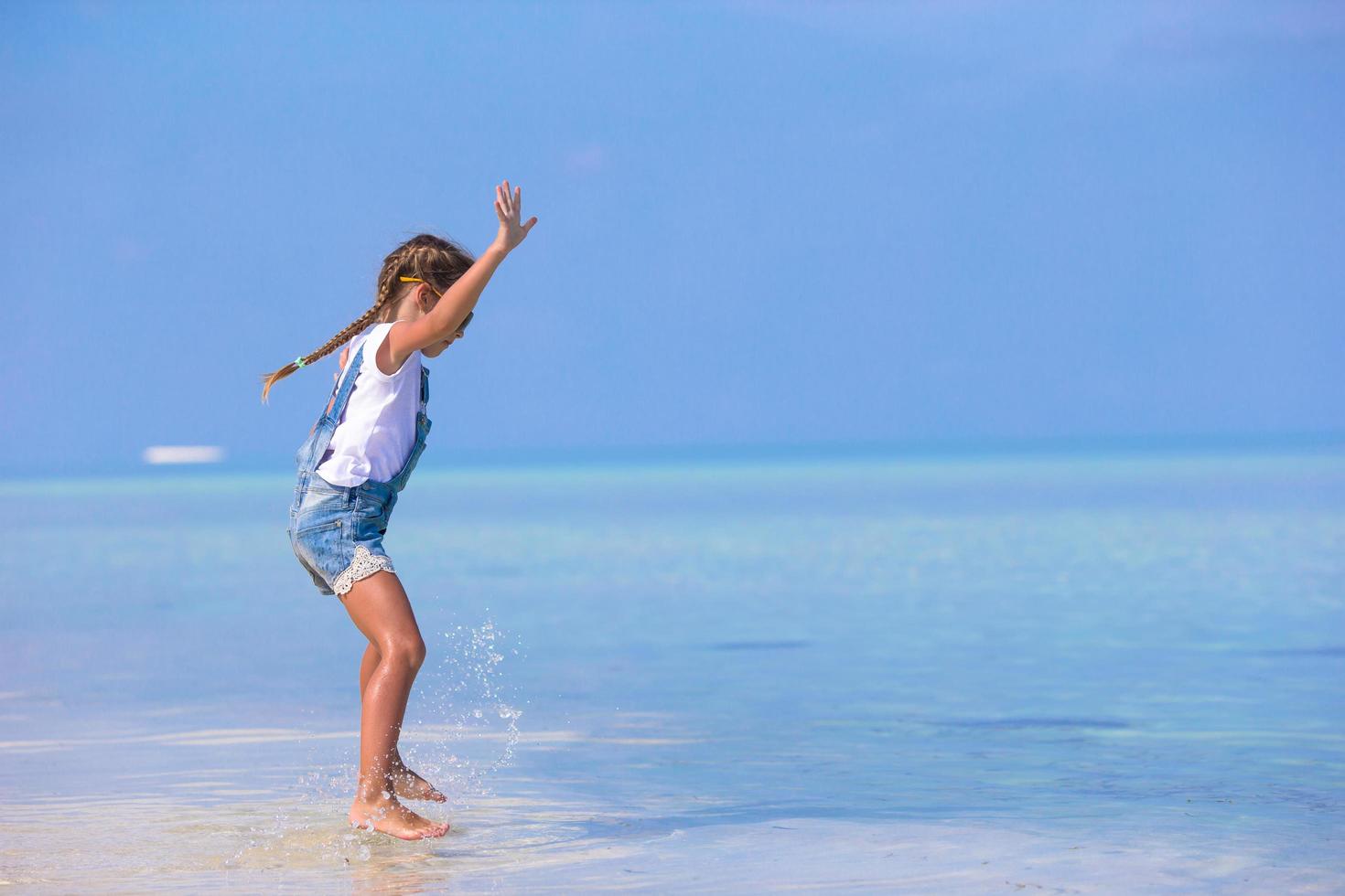 flicka som hoppar i vattnet på stranden foto