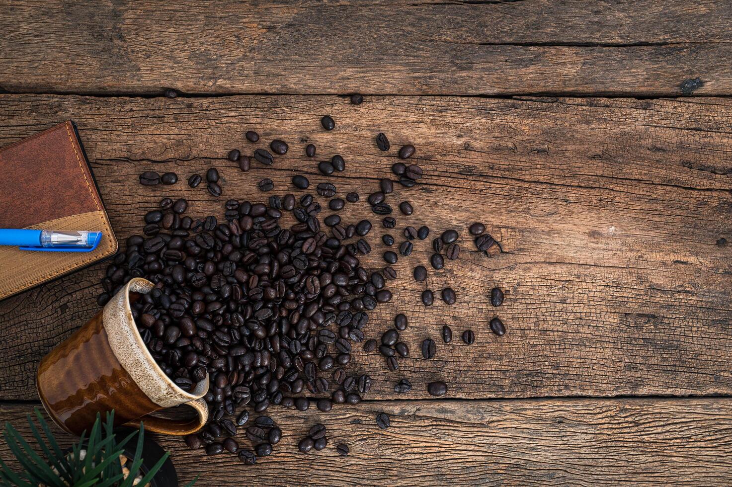 träskrivbord med anteckningsbok och kaffebönor foto