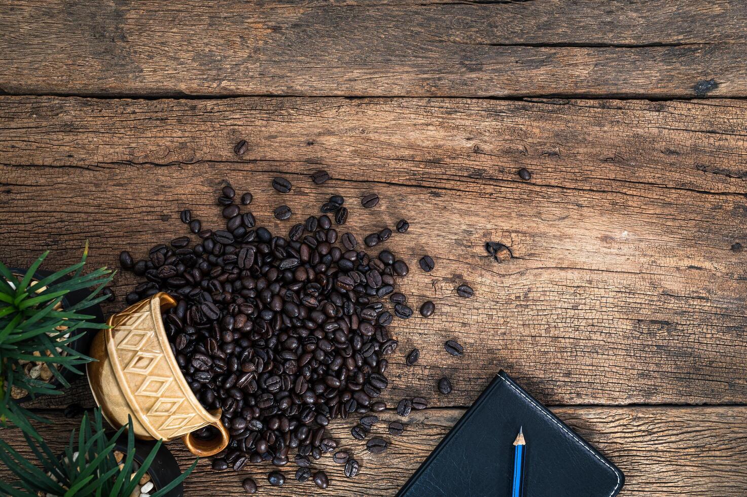 träskrivbord med anteckningsbok och kaffebönor foto