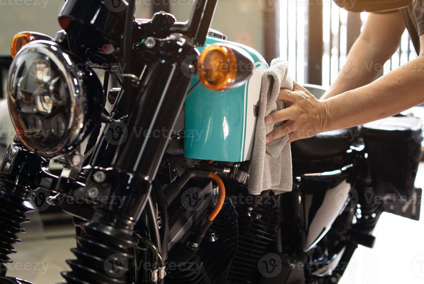 cyklist man rengöring motorcykel , polerad och beläggning vax på bränsle tank på garage. reparera och underhåll motorcykel begrepp. foto