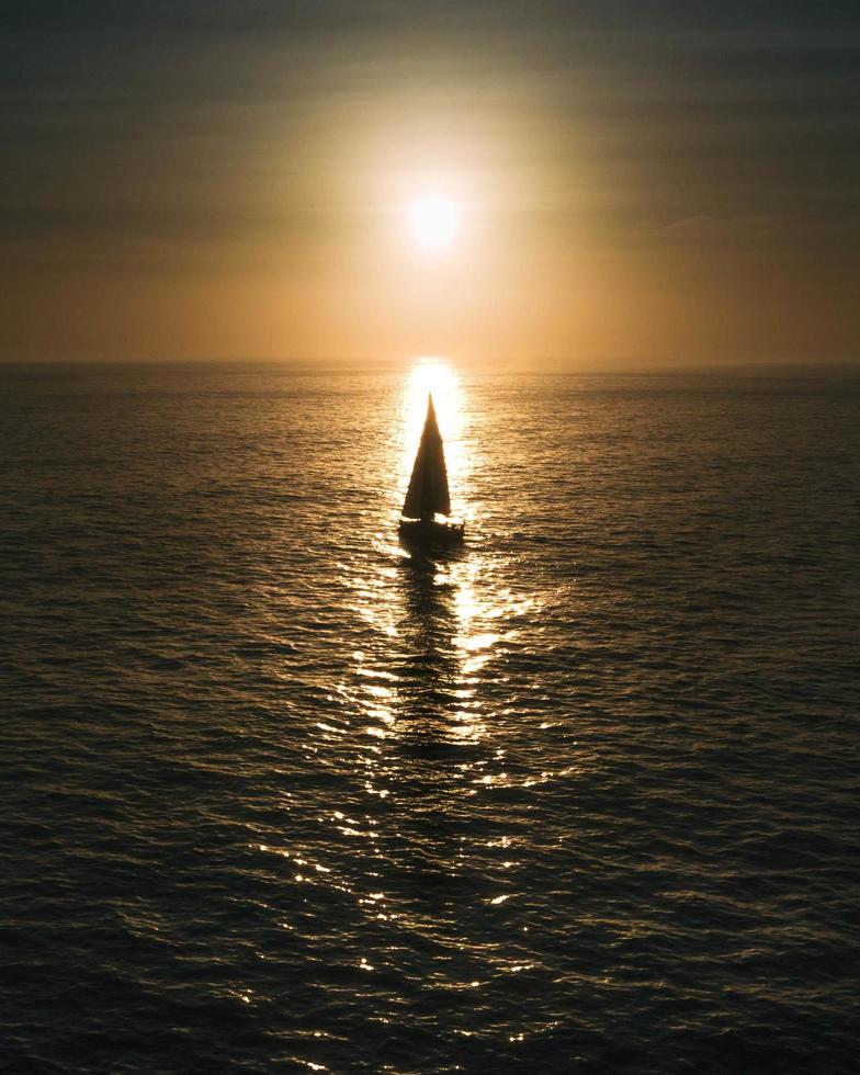 segelbåt på lugnt hav vid gyllene timmen foto