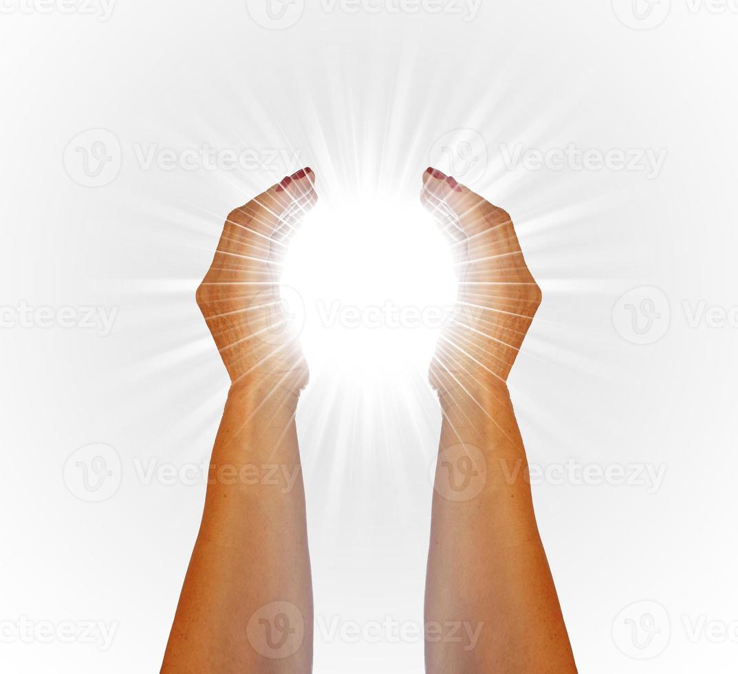 strålar av vit ljus mellan de händer av en kvinna på vit bakgrund foto