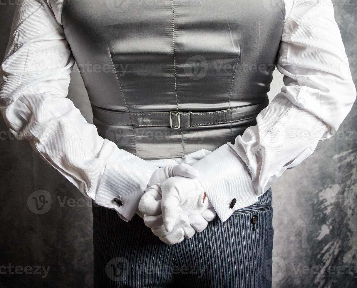 närbild av butler eller servitör i vit handskar stående med händer Bakom tillbaka. begrepp av service industri och elegant gästfrihet. foto
