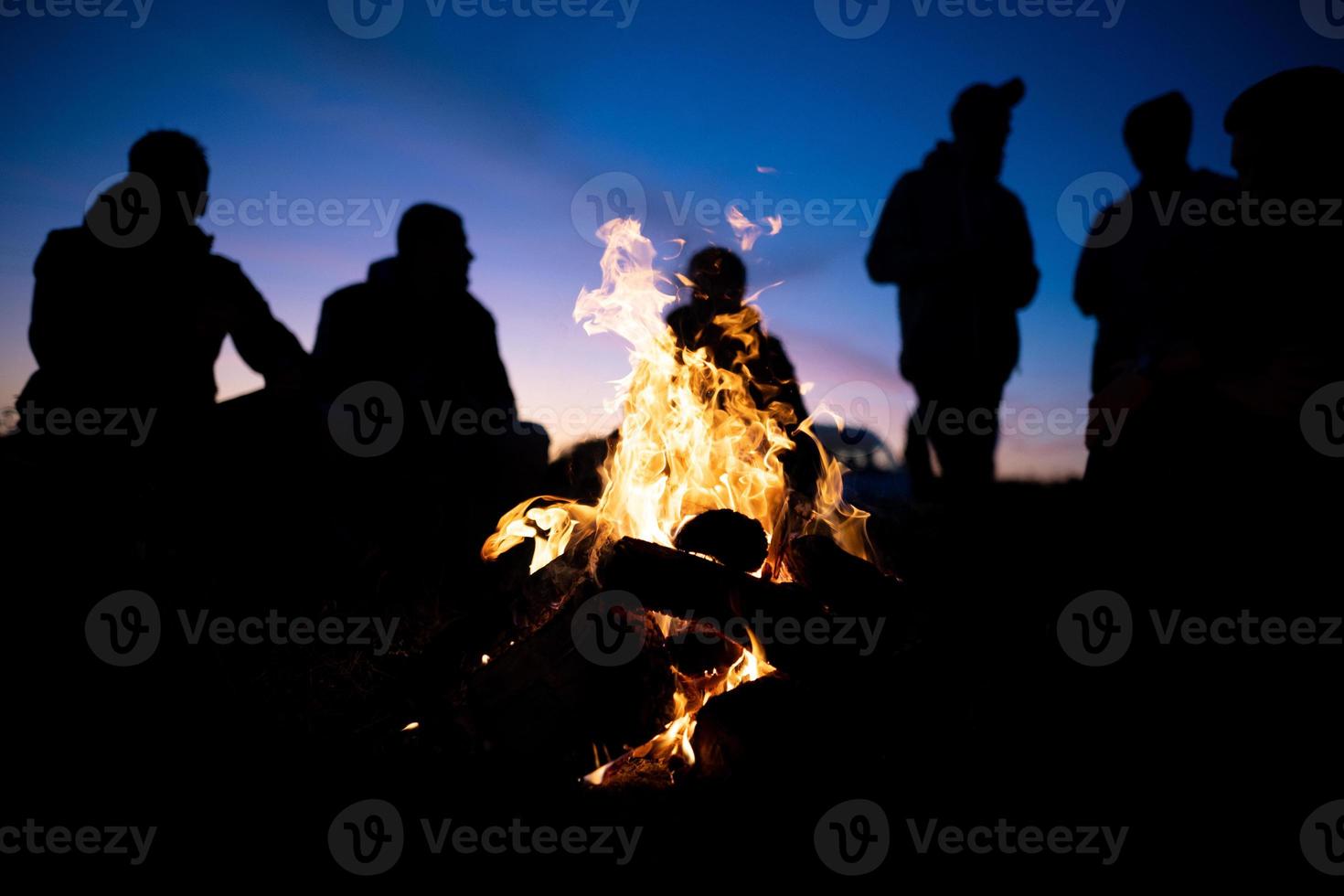 en grupp av vänner samlade in runt om de brand på natt foto