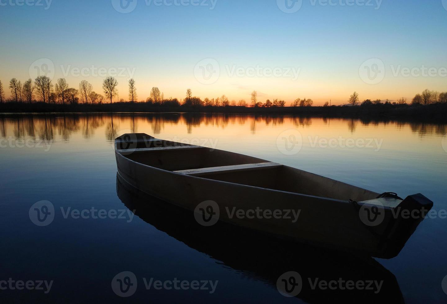 trä- båt på en stor skön sjö på solnedgång. foto