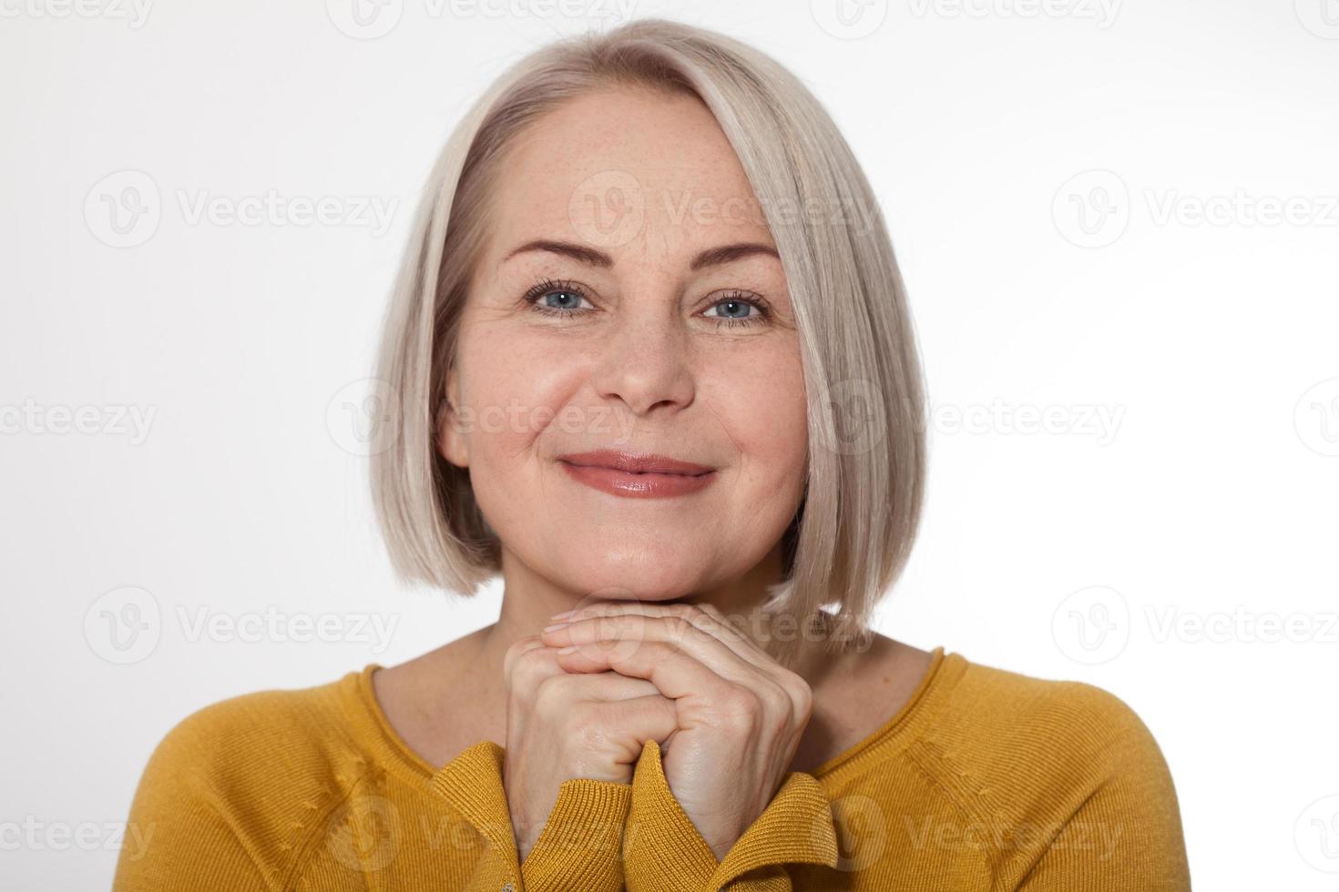 mitten åldrig blond känslomässigt Framställ i en studio. Lycklig kvinna i gul ljus Tröja på vit bakgrund foto