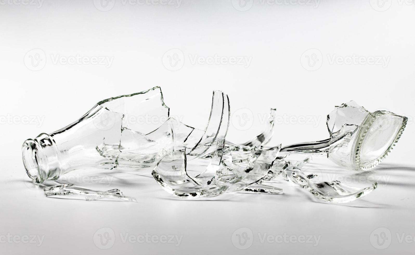 en glas flaska bruten in i många fragment på en grå bakgrund. foto